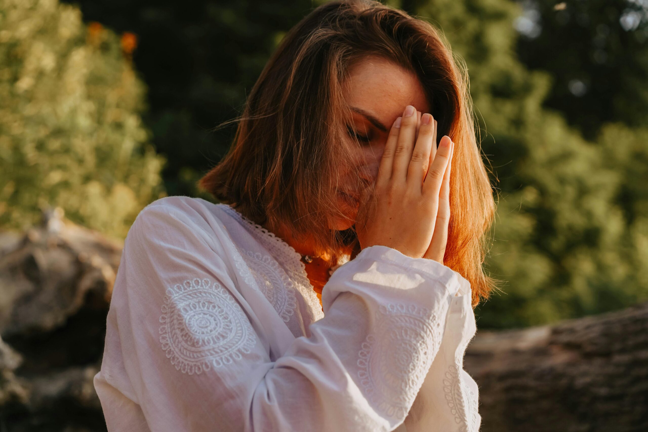 Woman praying outdoors with hands covering her face – World Prayer Center prayer and spiritual support